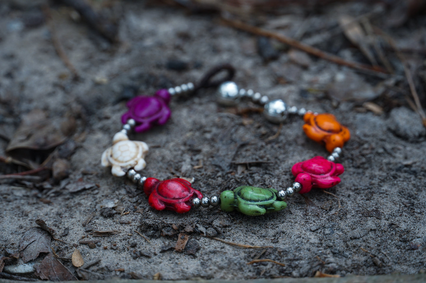 Colorful handmade bracelet featuring beads and flowers, crafted from turtle silver and cotton cord by Thai artisans.