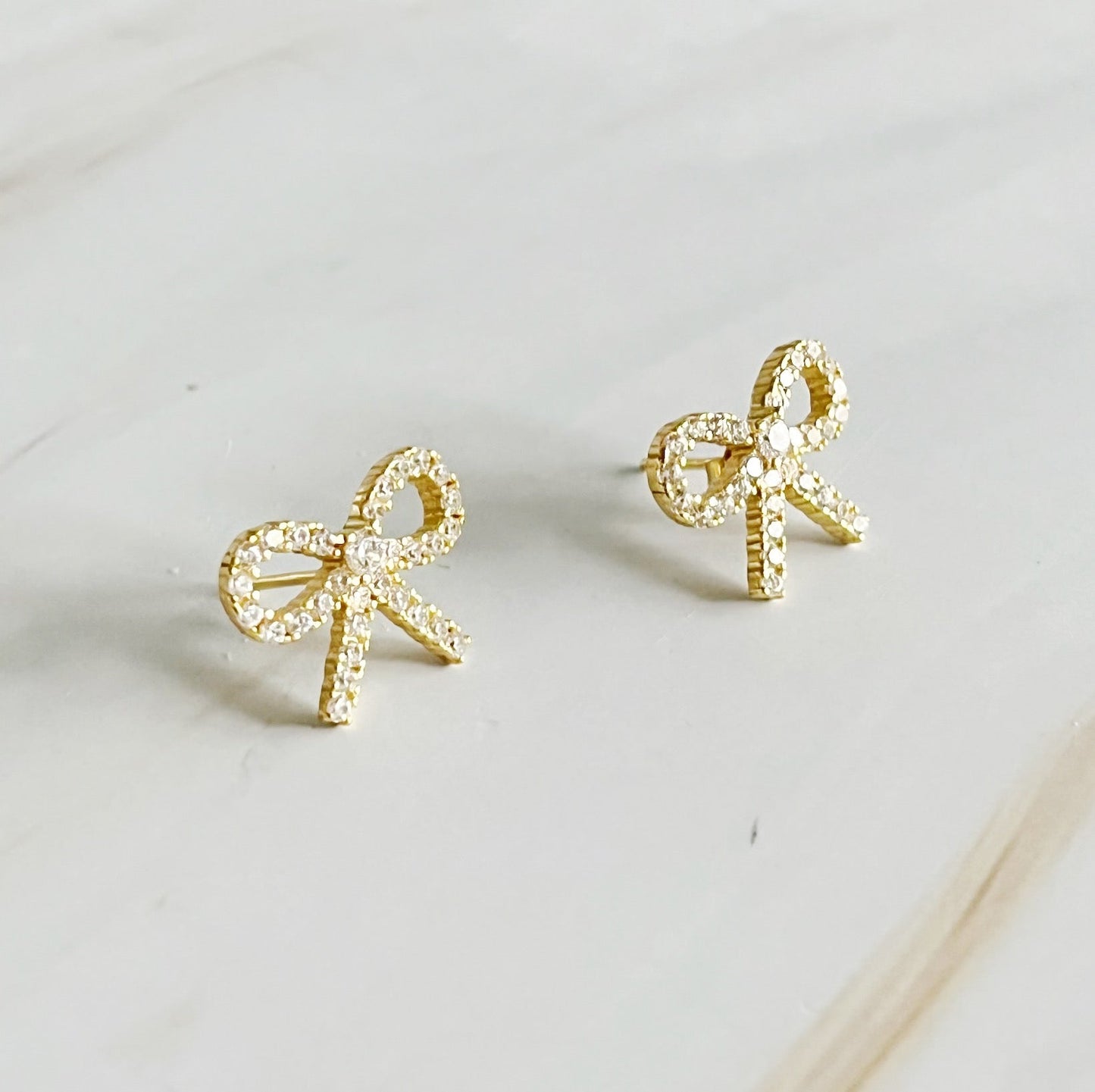 Elegant gold bow stud earrings crafted from sterling silver, adorned with cubic zirconia, perfect for any outfit