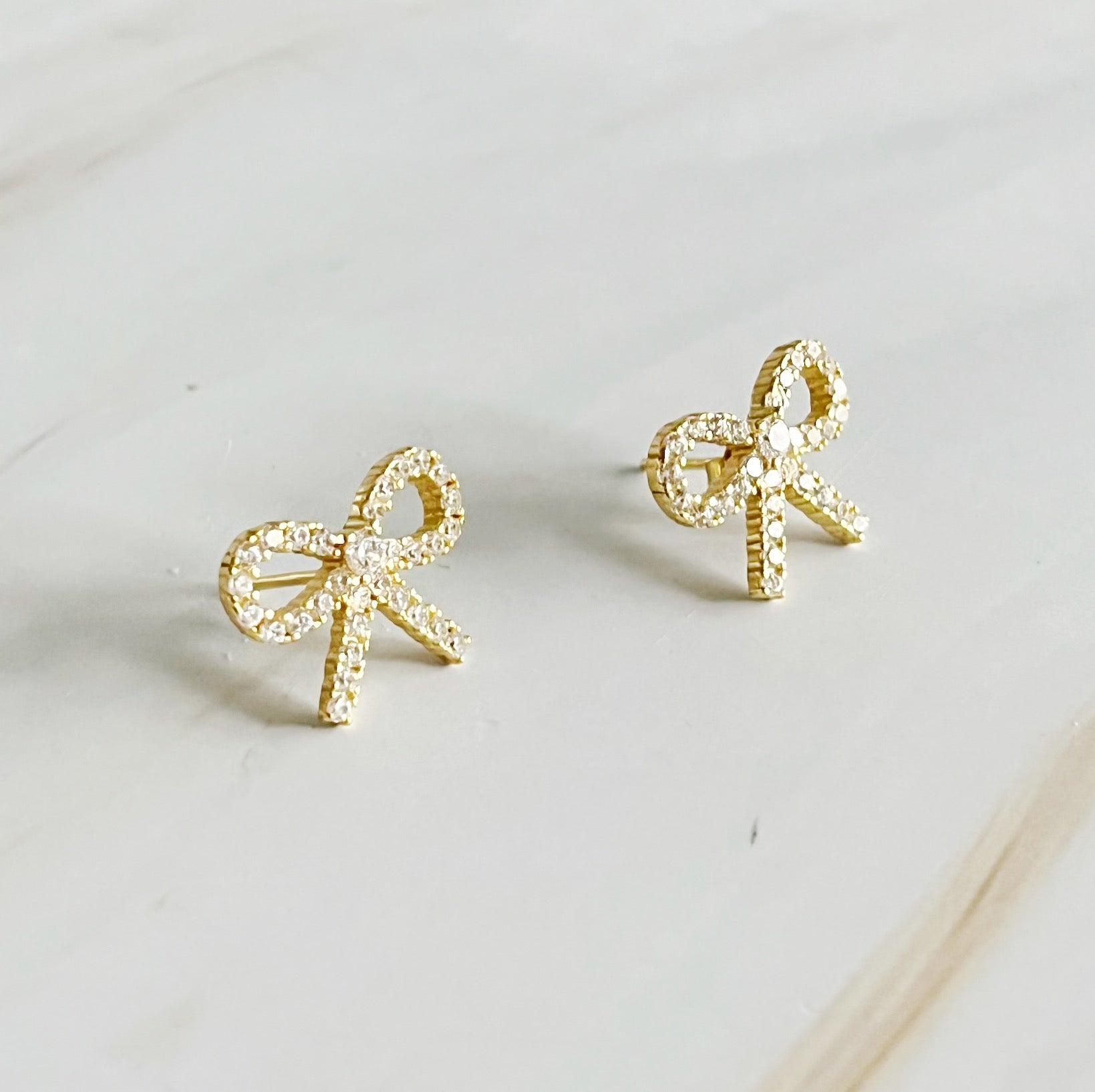 Elegant gold bow stud earrings crafted from sterling silver, adorned with cubic zirconia, perfect for any outfit