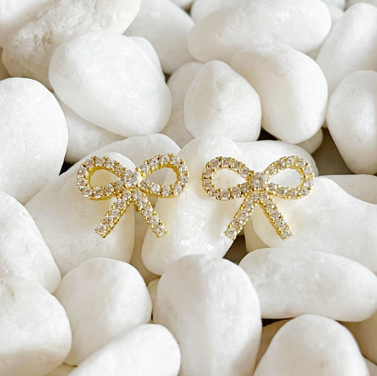  Two gold bow stud earrings on white stones, crafted from 18k gold plated sterling silver with cubic zirconia accent
