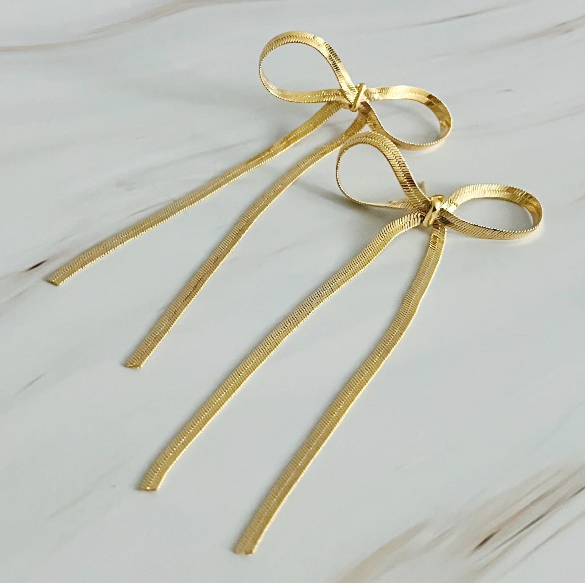 Long drop bow earrings in 18k gold plated brass, adding sophistication and charm to any outfit. Dimensions: 1.5" x 3".