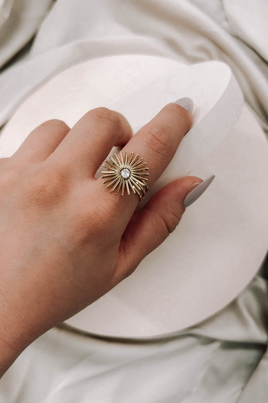 A woman's hand showcases a sunflower ring featuring a crystal
on a gold band, adjustable to fit sizes 6 through 9.

