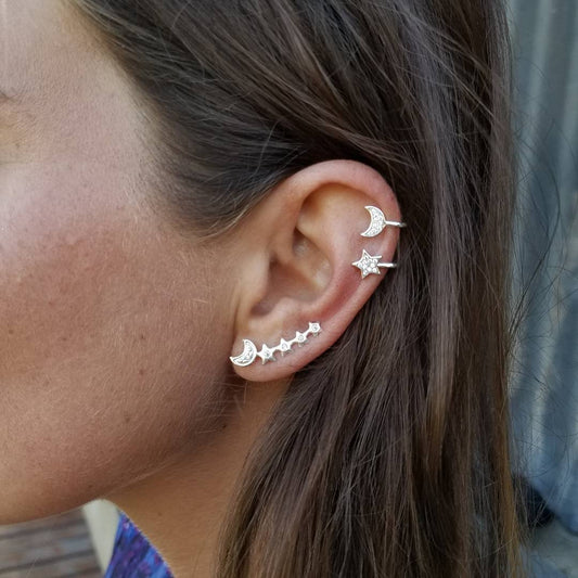 A woman showcases an ear cuff set featuring stars and a moon, designed for an asymmetrical look with high-quality materials.