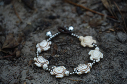 Handmade turtle silver bracelet with shells, featuring pressed cotton cord, perfect for a boho or beach-themed style.