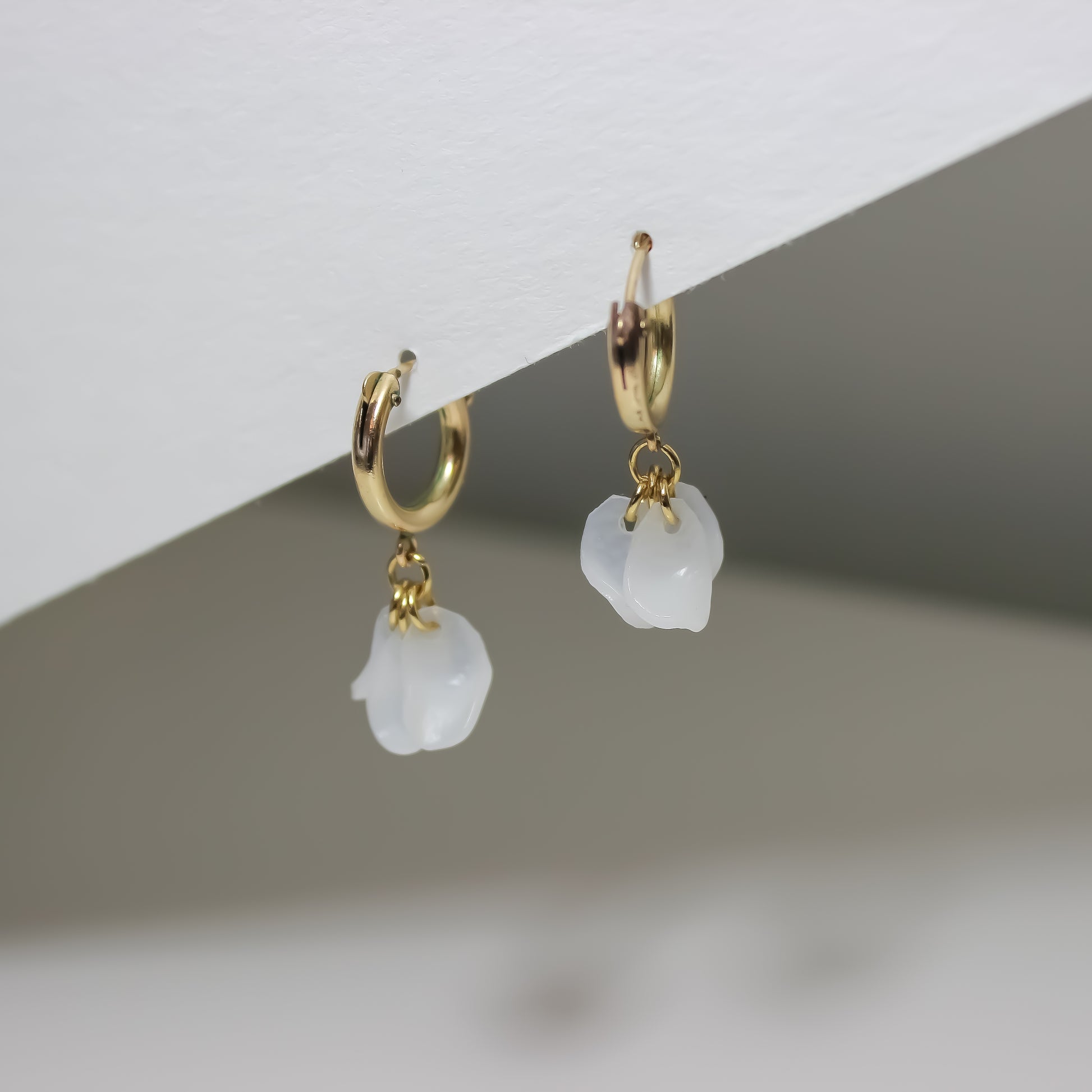 White stone earrings with a gold chain, featuring a flower pendant, handmade from recycled materials in Arlington, VA.