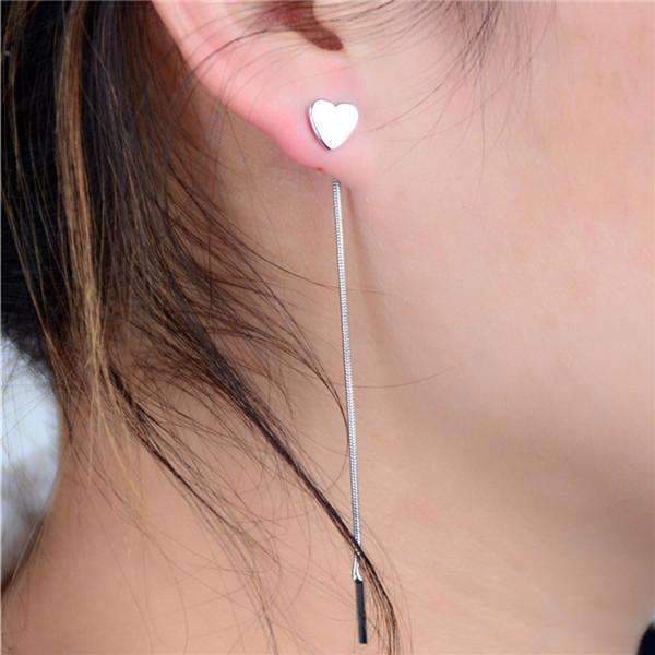  A woman wearing 8 cm heart-shaped drop earrings made of alloy, showcasing a stylish and playful accessory