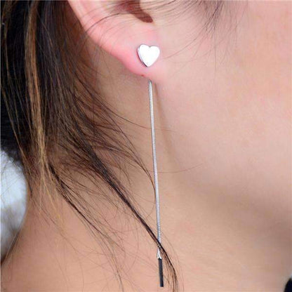  A woman wearing 8 cm heart-shaped drop earrings made of alloy, showcasing a stylish and playful accessory