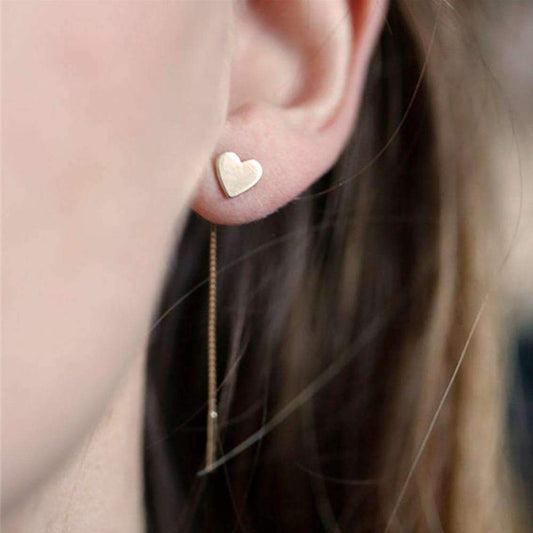 A woman displays gold heart-shaped drop earrings, measuring 8 cm, crafted from alloy, adding elegance to her look.