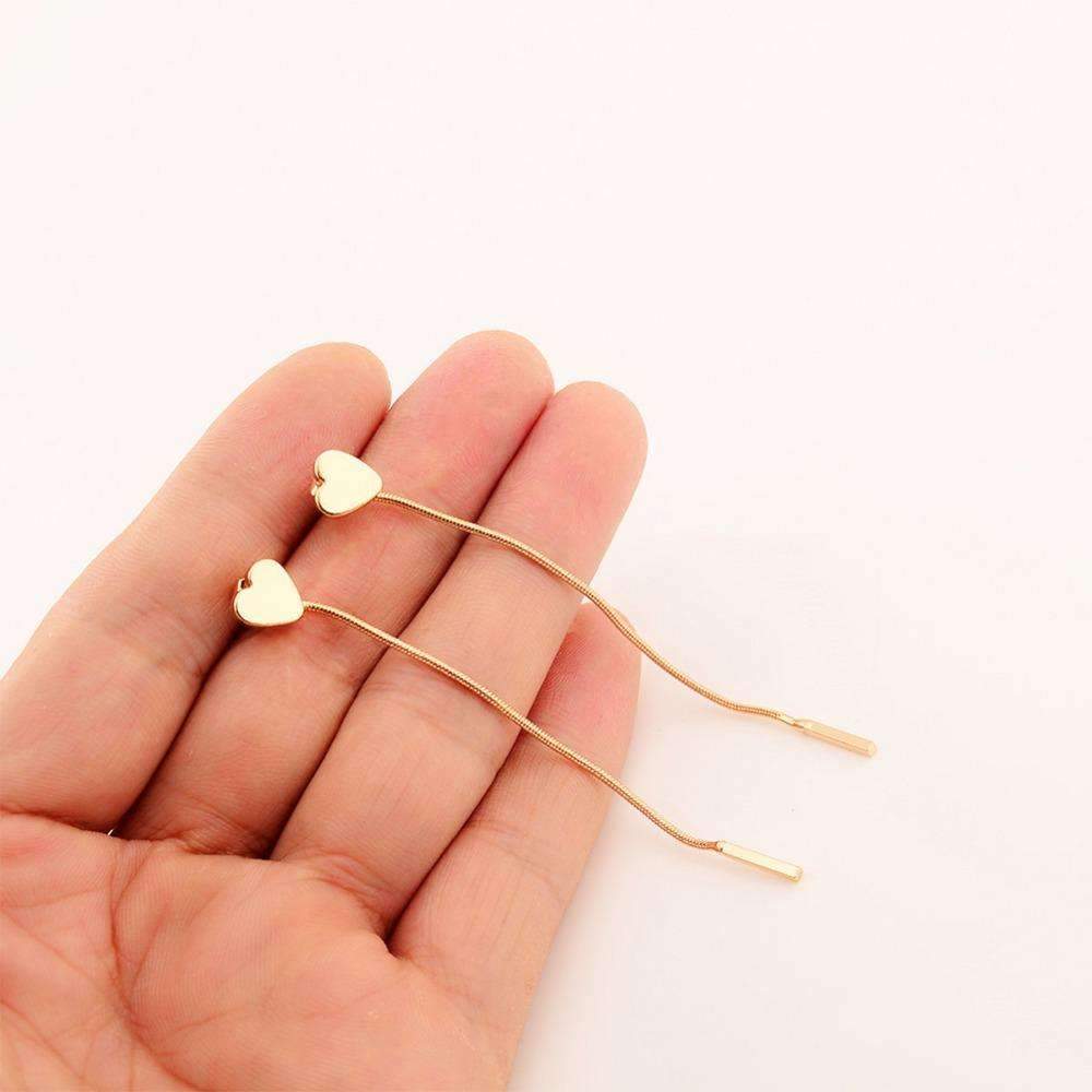 Two gold heart-shaped hair pins resting on a hand, showcasing their elegant design and shiny finish.
