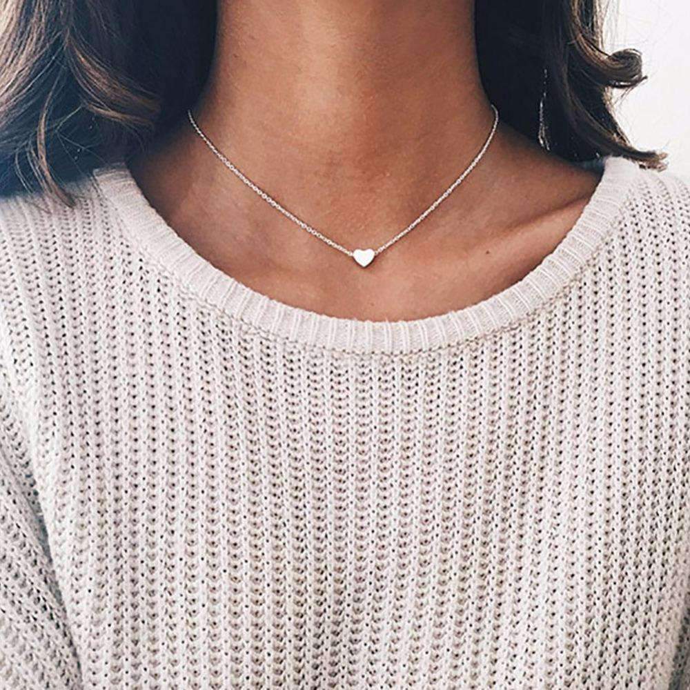  A woman in a white sweater wears a silver heart pendant
necklace, showcasing its elegant design and quality materials