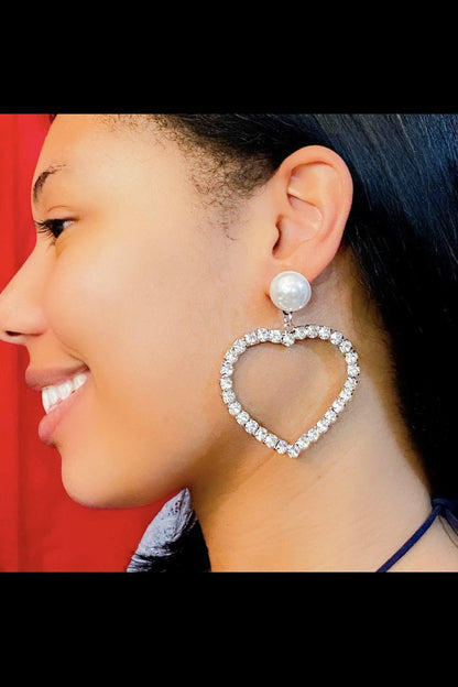 A woman models stylish silver heart-shaped drop earrings,
made from nickel-free zinc alloy, suitable for various occasions.
