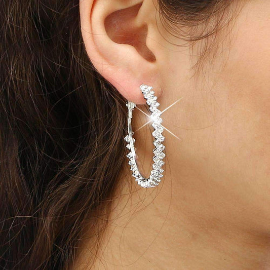 A woman showcases diamond hoop earrings with a zig-zag design, crafted from zinc alloy, offered in 1.69" and 2.04" diameters.