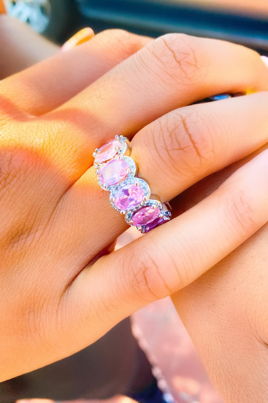 A woman's hand showcases a pink and purple stackable
diamond ring set in high polished 14K white gold.
