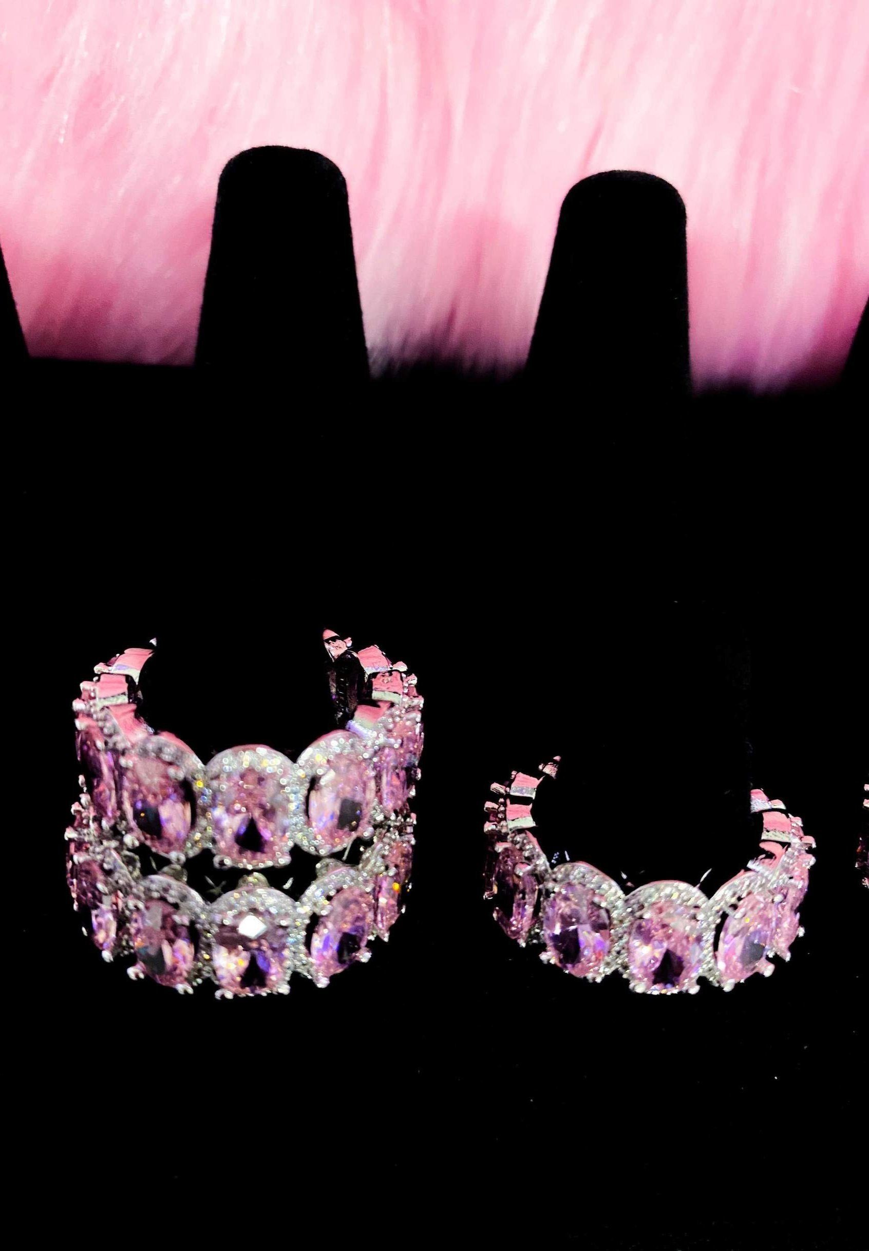 Three pairs of pink diamond earrings arranged on a black
background, highlighting their exquisite design and sparkle