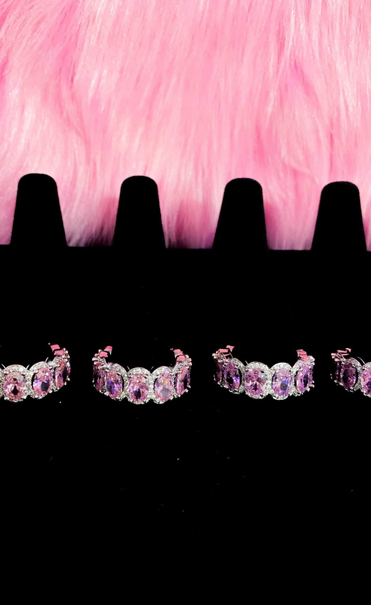 Three pairs of pink diamond earrings arranged on a black
background, highlighting their exquisite design and sparkle