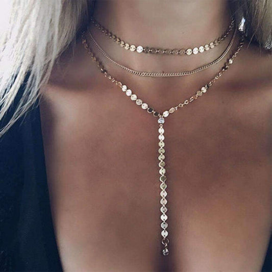 A woman models a three-layer necklace featuring a gold chain and two rhinestone pendants, showcasing elegant jewelry design.