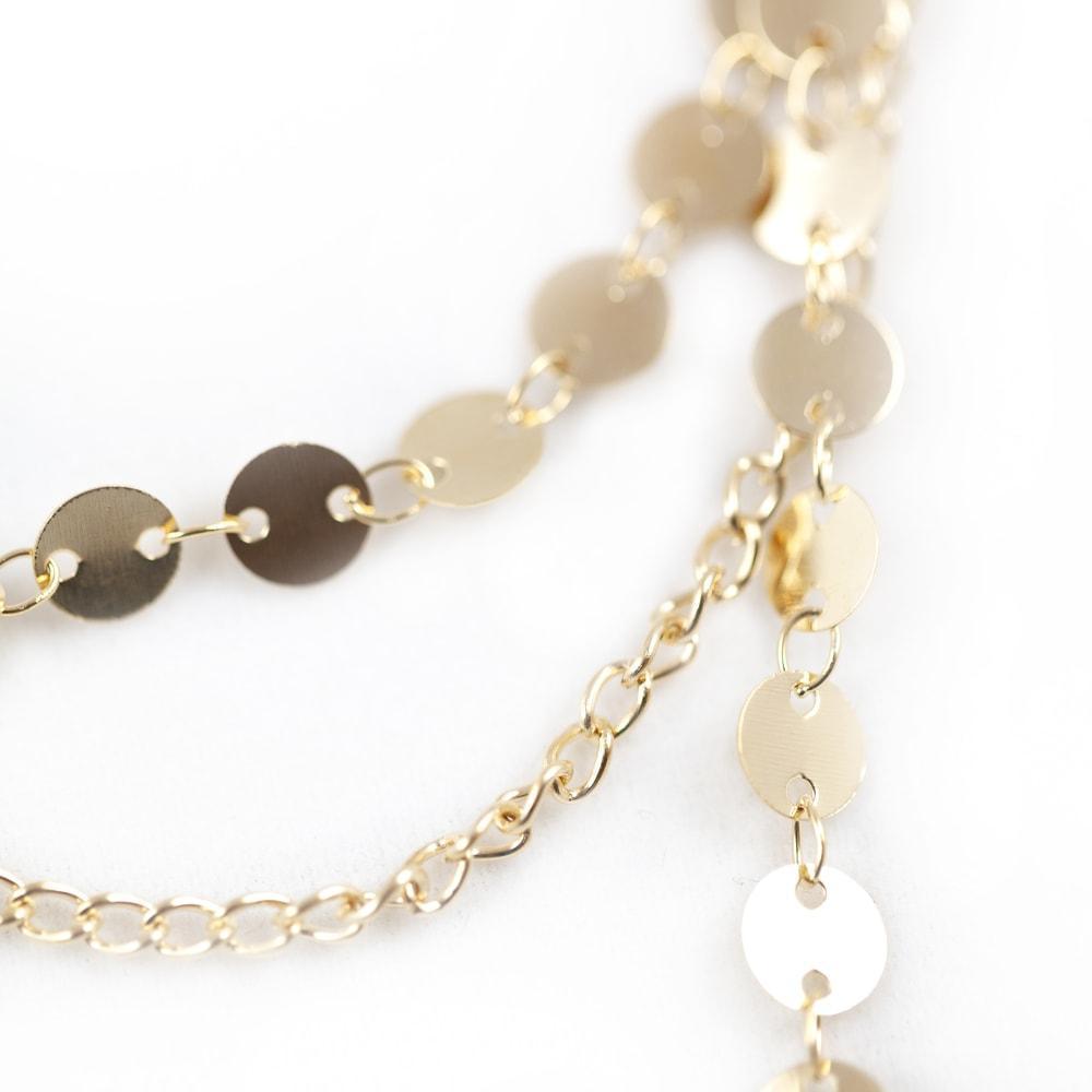 Close image of a gold chain necklace with decorative circles and discs, emphasizing its stylish design