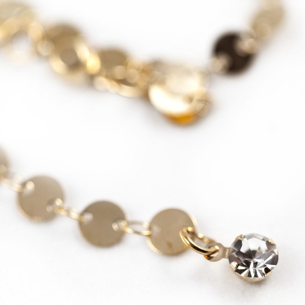  Close-up image of a gold chain with a stylish crystal pendant, emphasizing the intricate details and elegance of the piece