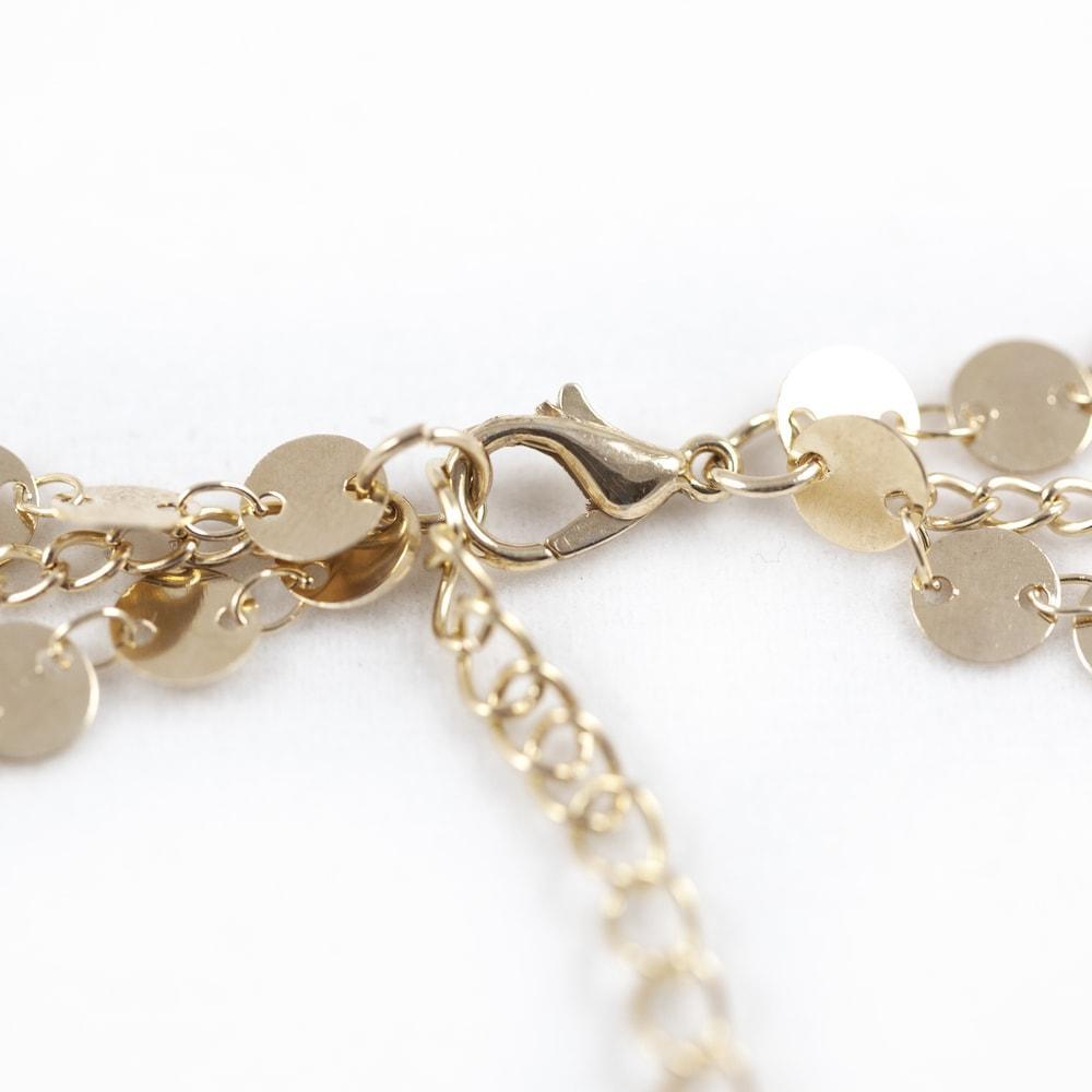 Close-up of a gold chain featuring a circular disc pendant and an intricate chain design