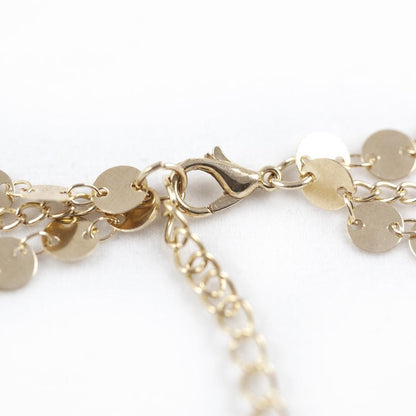 Close-up of a gold chain featuring a circular disc pendant and an intricate chain design