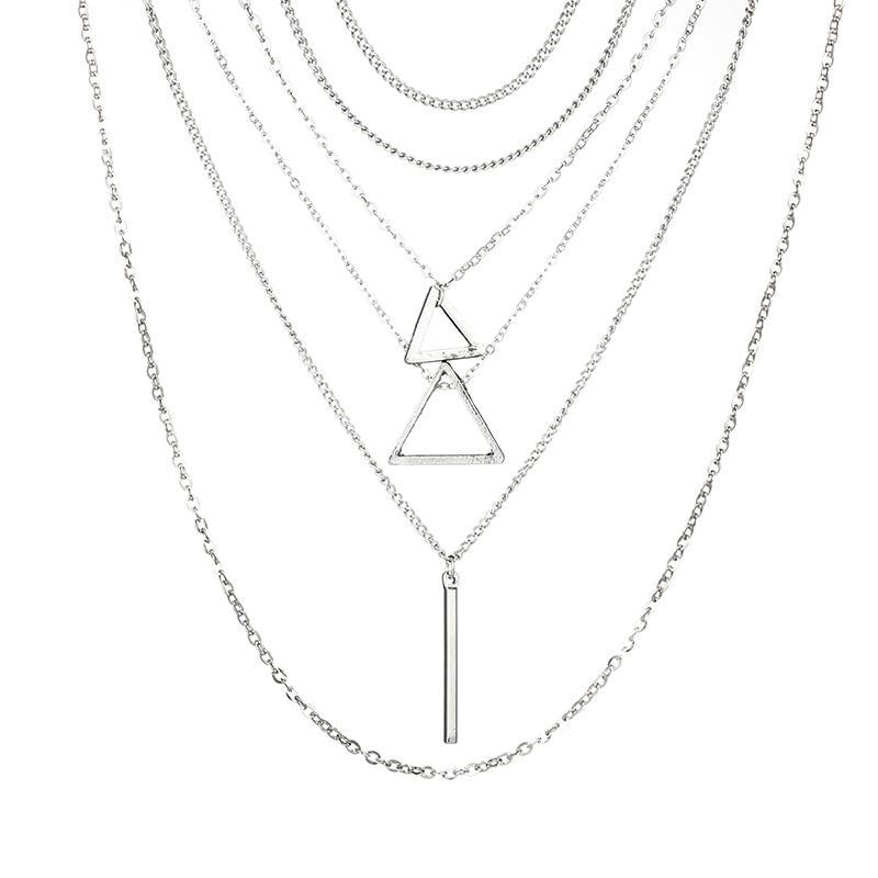 A layered collection of silver necklaces with two triangles, one vertical bar, two chokers, and one long adjustable chain