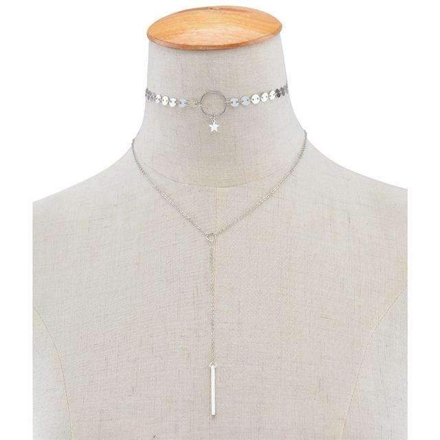  A silver two-layer necklace on a mannequin neck features a star and circle choker with a long adjustable lariat.